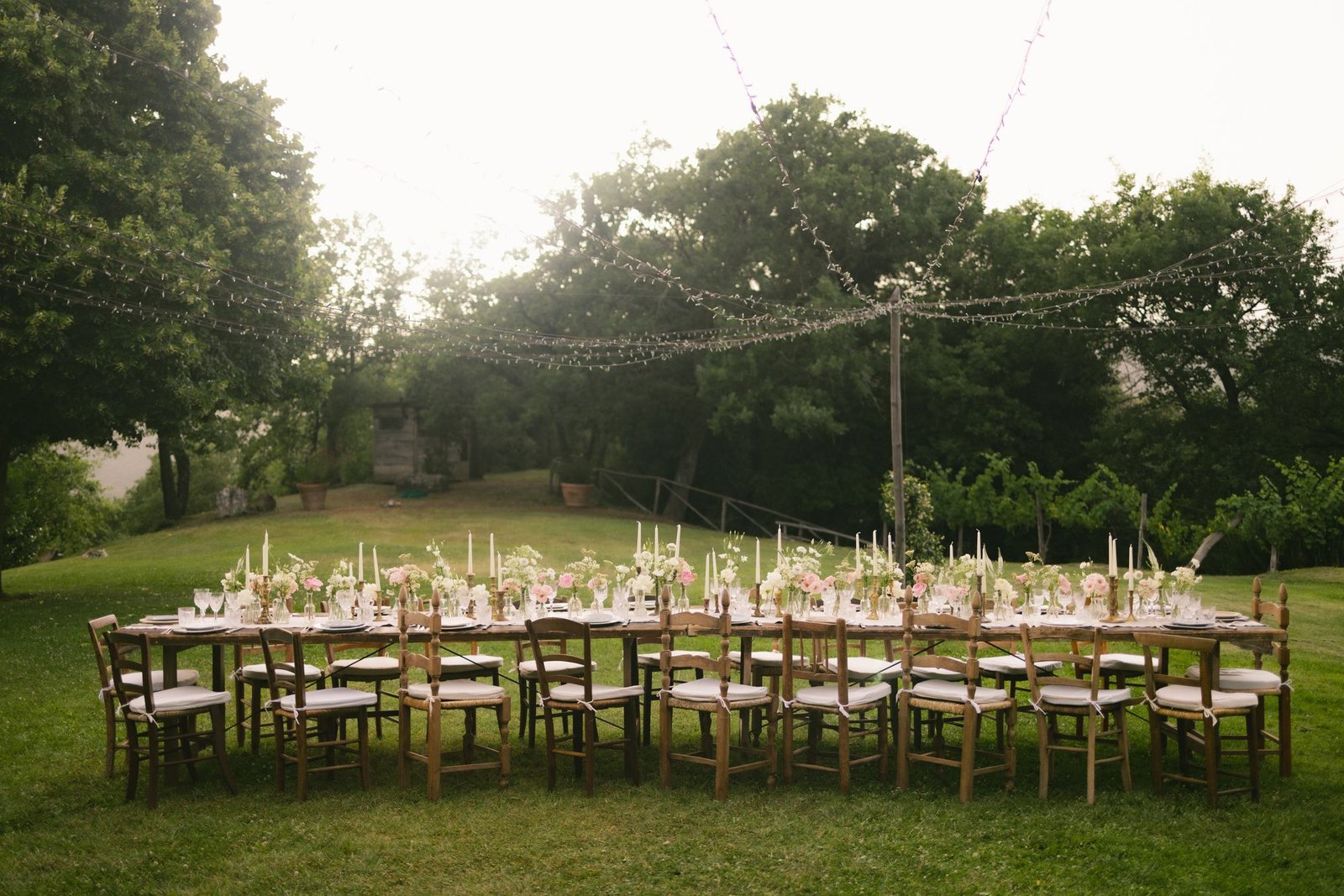 An elegant outdoor celebration with tables arranged in a garden